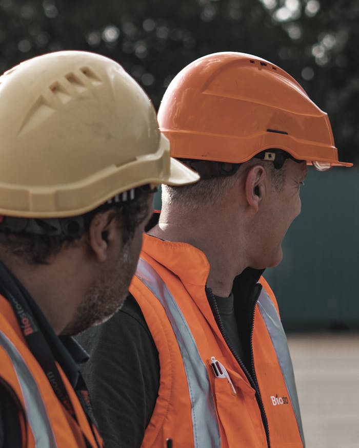 ours-journey Two construction workers wearing safety helmets and vests on a site.