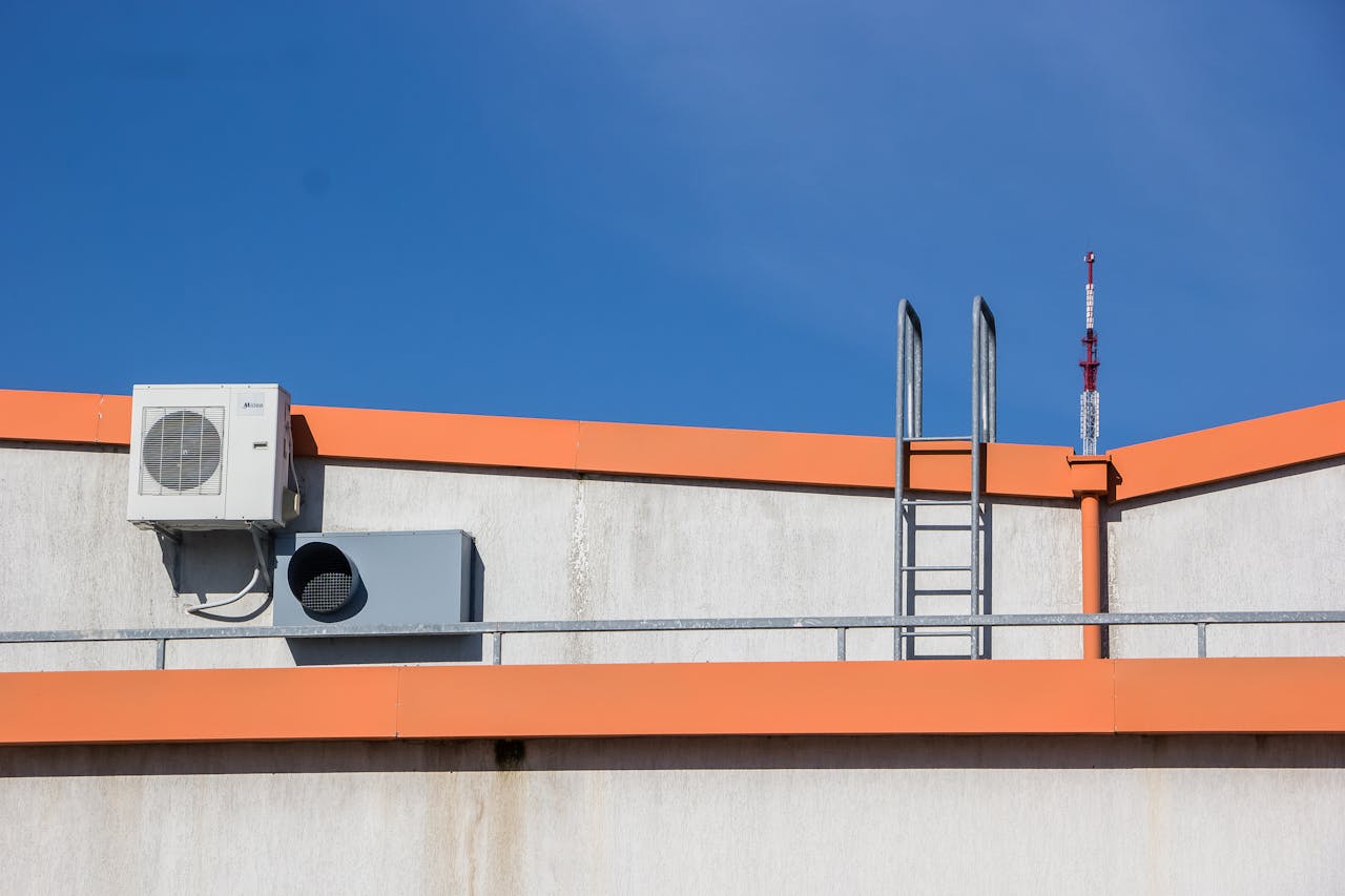 services-02 Rooftop view with HVAC unit, ladder, and clear sky background.