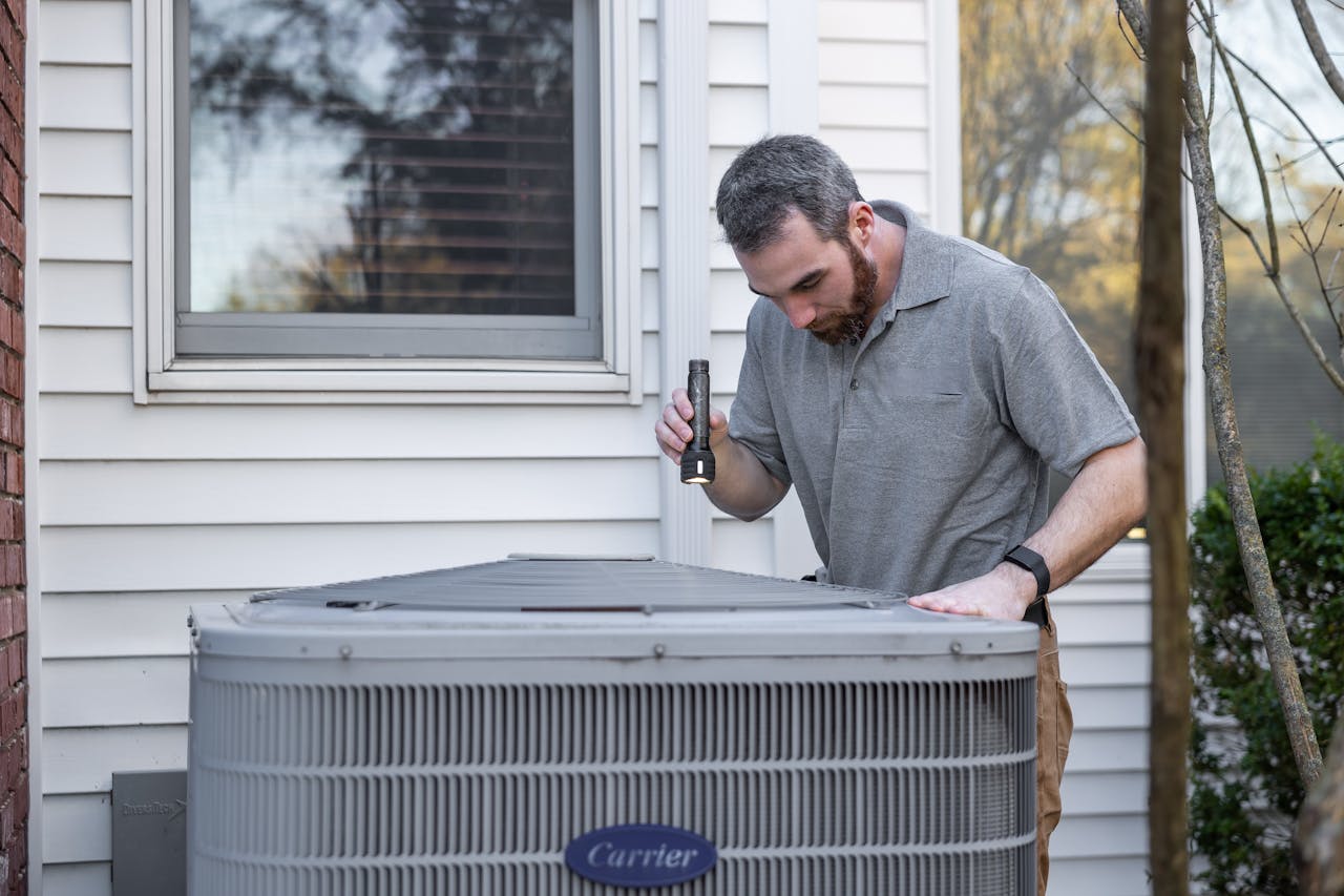 gallery-4 A technician inspects an outdoor HVAC unit for maintenance.