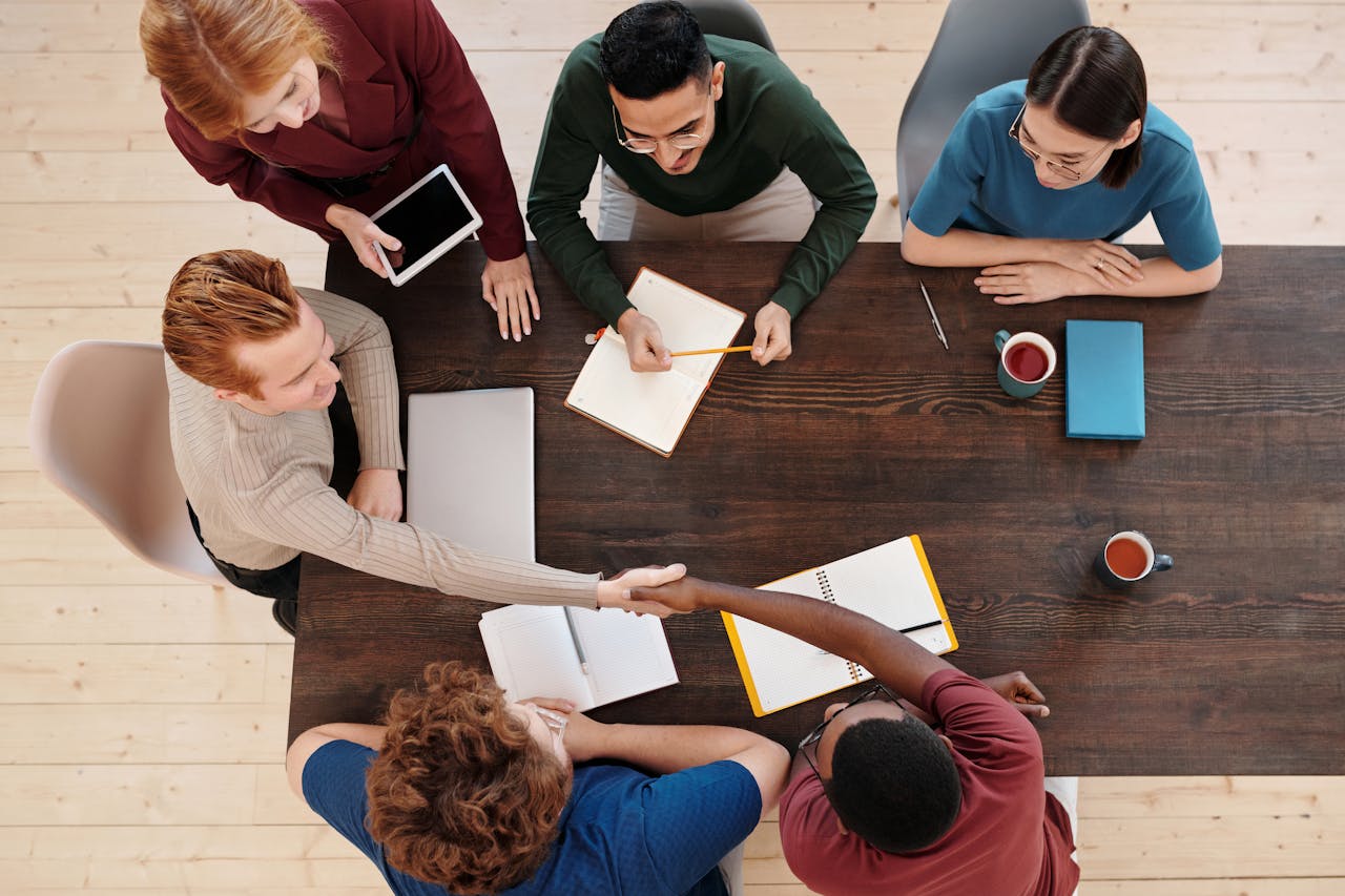 services-02 Top view of a diverse business team meeting with a handshake across the table. Collaborative working environment.
