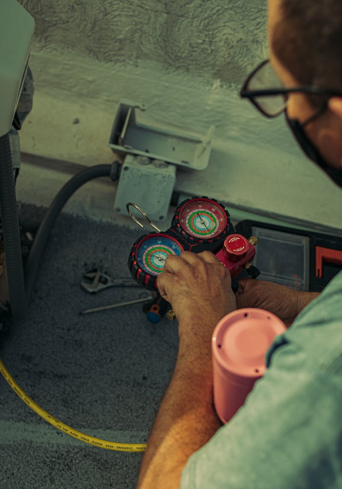 gallery-3 Professional technician adjusting a refrigerant manifold gauge for air conditioning maintenance.