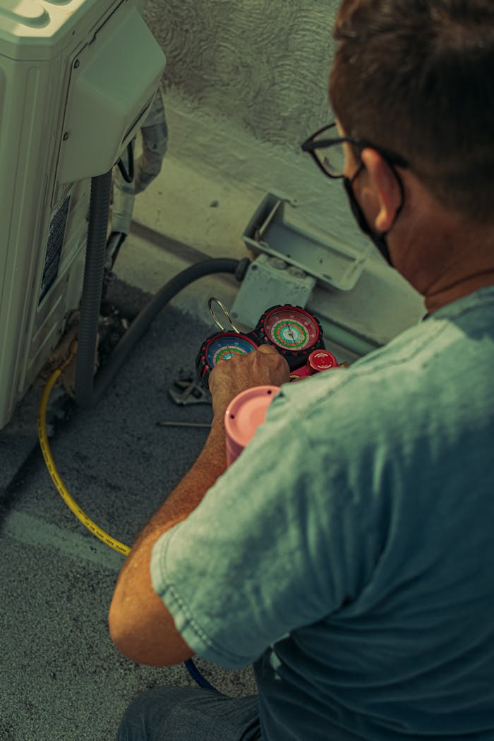 gallery-2 Professional technician repairing an outdoor air conditioning unit with gauges and tools.
